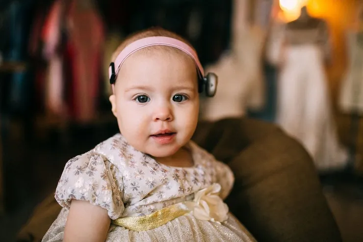 baby-girl-hearing-device Baby girl in beautiful dress with matching hearing device