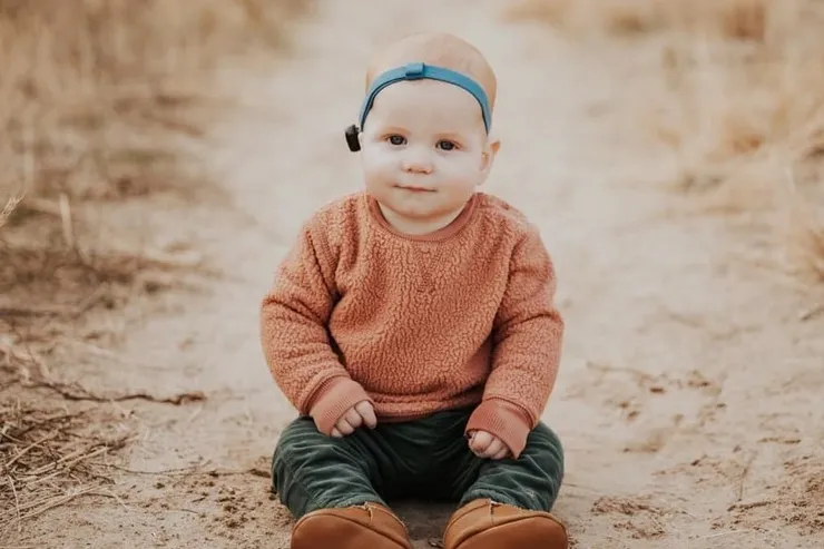 baby-hearing-device Baby sitting up wearing hearing device
