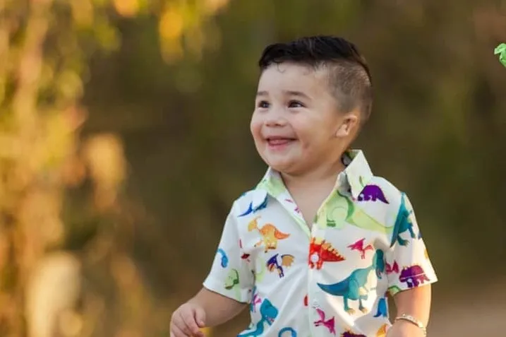 happy-toddler Young boy with microtia in dinosaur shirt