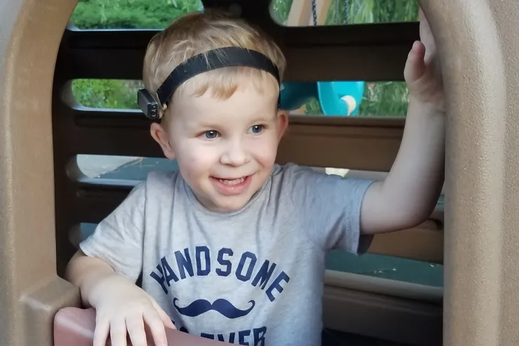 Smiling toddler wearing a hearing device