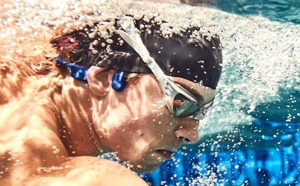 swimming-with-shokz-openSwim Person swimming with blue SHOKZ OpenSwim mp3 headphones