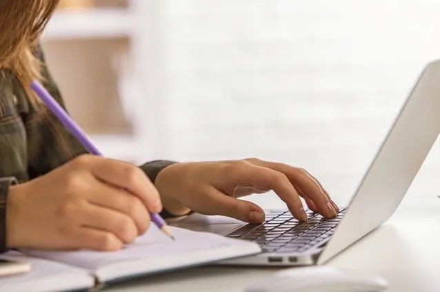 A person taking notes from their laptop